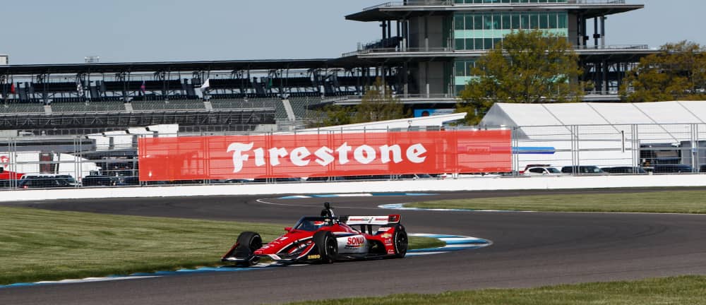 Formula race car on track, under Firestone banner